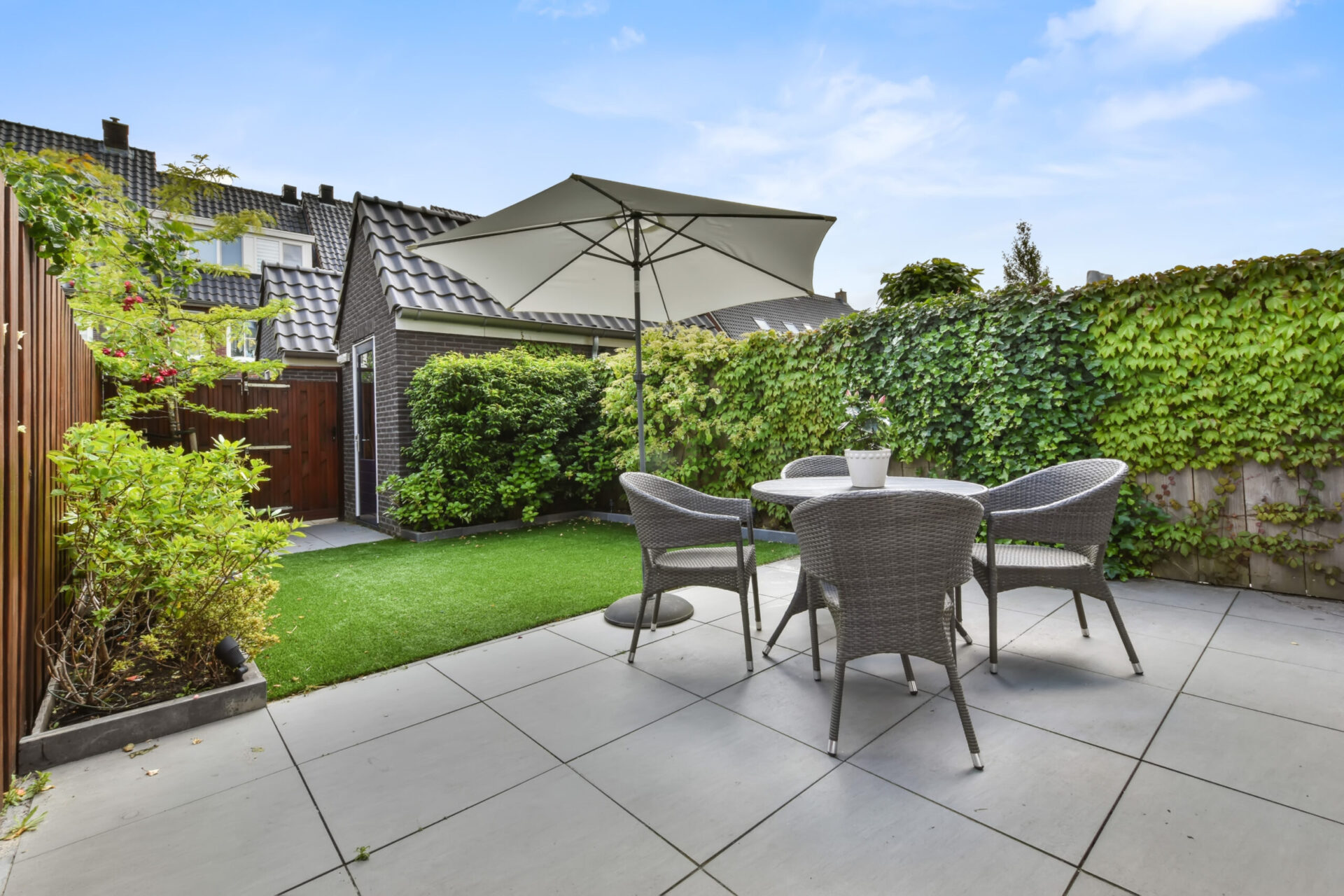 Hinterhof in einem gemütlichen Haus mit kleiner Sitzecke und Garten der mit Terrassenplatten gepflastert ist